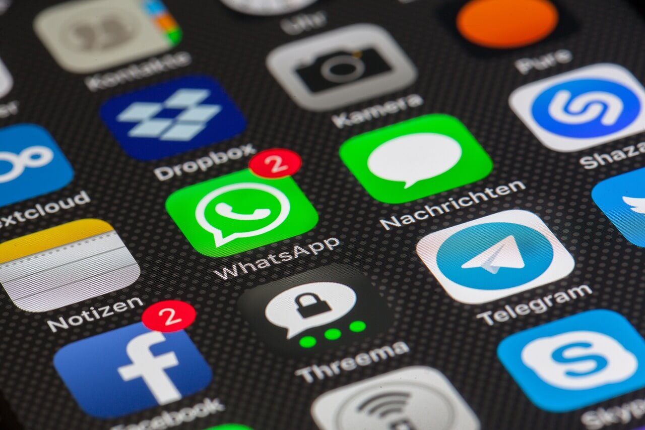 A tela móvel mostra vários aplicativos, incluindo o WhatsApp.